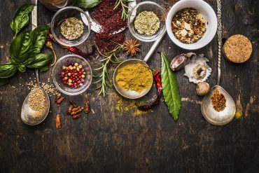 Dry colorful spices with fresh seasoning on rustic wooden background