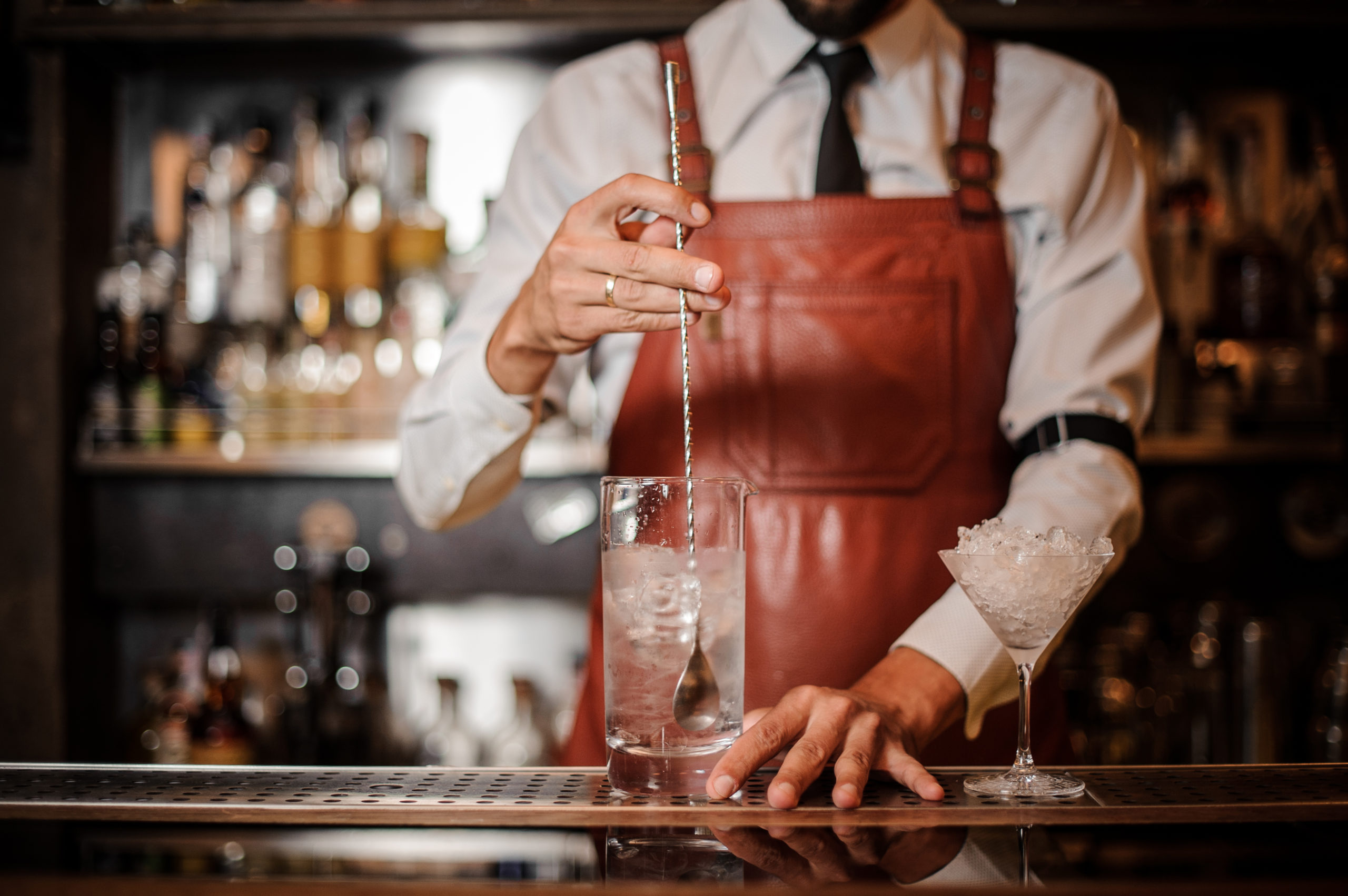 Bartender stirring an ice cubes in the cocktail Azuñia Tequila